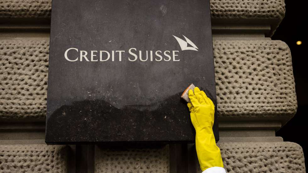 epa10619151 An activist of Scientist Rebellion cleans symbolically the sign at the entrance of the Swiss Bank Credit Suisse at Paradeplatz during a protest against fossil fuel investments, in Zurich, Switzerland, 10 May 2023.  EPA/MICHAEL BUHOLZER