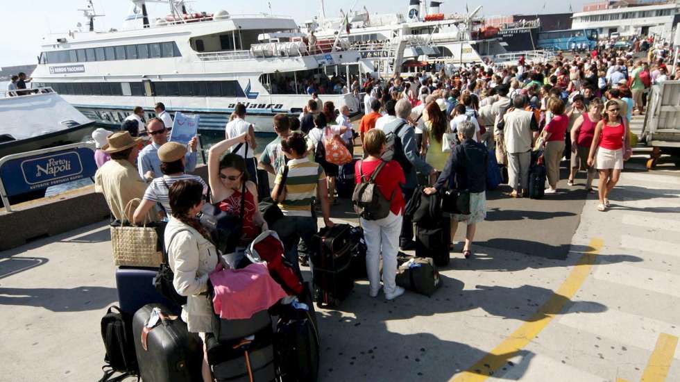 epa000482586 Numerous tourists wait in line at Beverello wharf, Saturday 16 July 2005, to embark boats for the islands of the gulf of Naples, like Goats, Ischia and Procida, which are popular destinations for the tourists of Italy's Campania region.  EPA/CIRO FUSCO