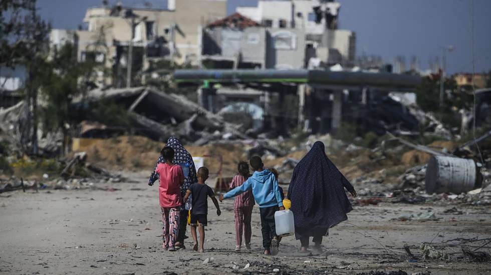 epaselect epa11392513 Internally displaced Palestinians walk next to destroyed buildings in Khan Younis, southern Gaza Strip, 05 June 2024. More than 36,000 Palestinians and over 1,400 Israelis have been killed, according to the Palestinian Health Ministry and the Israel Defense Forces (IDF), since Hamas militants launched an attack against Israel from the Gaza Strip on 07 October 2023, and the Israeli operations in Gaza and the West Bank which followed it.  EPA/MOHAMMED SABER