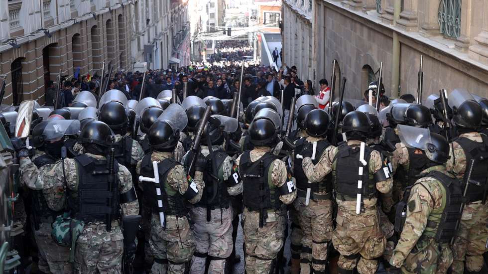 epa11440767 Military police line up in front of supporters of Bolivian President Luis Arce during a protest against military personnel trying to enter the government headquarters in La Paz, Bolivia, 26 June 2024. A group of soldiers led by Bolivian Army general commander Juan Jose Zuniga entered Plaza Murillo on 26 June 2024 using a tank to knock down the door of the government headquarters. The soldiers withdrew after Bolivian President Luis Arce changed the heads of the entire military high command, describing the action as a coup attempt.  EPA/Luis Gandarillas