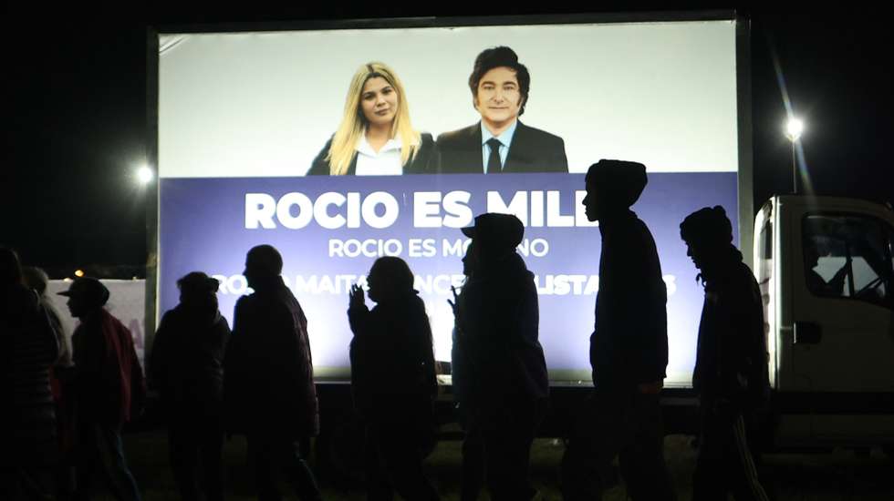 epa12350652 People walk past a fence featuring an image of Argentina's President, Javier Milei, during a campaign closing event for his party, La Libertad Avanza (LLA) in Moreno, Argentina, 03 September 2025.  EPA/Juan Ignacio Roncoroni
