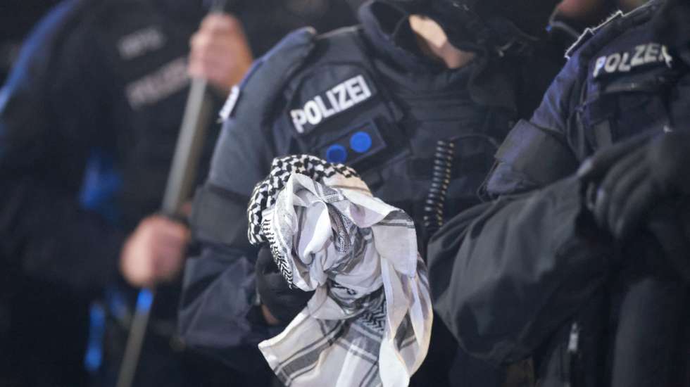 epa12438224 A police officer holds a keffiyeh of a detained person near the TV tower during a spontaneous pro Palestine demonstration on the second anniversary of the Hamas attack against Israel near Alexanderplatz square in Berlin, Germany, 07 October 2025.  EPA/CLEMENS BILAN