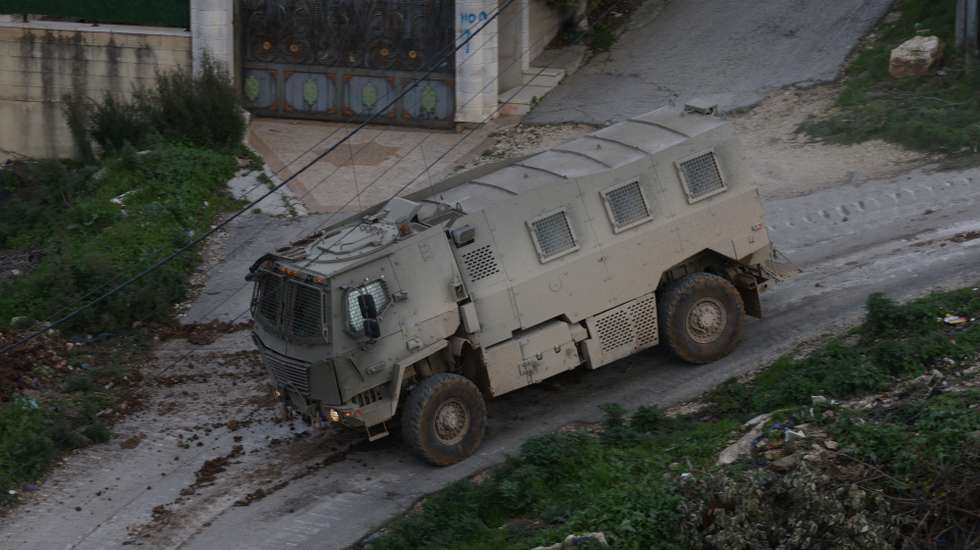 epa12644873 An Israeli army troop vehicle drives by during a military operation in Nur Shams refugee camp, near the West Bank city of Tulkarem, 12 January 2026. Israeli troops continue their operation in the Nur Shams refugee camp, east of Tulkarem, which has been under a tight Israeli siege since January 2025.  EPA/ALAA BADARNEH