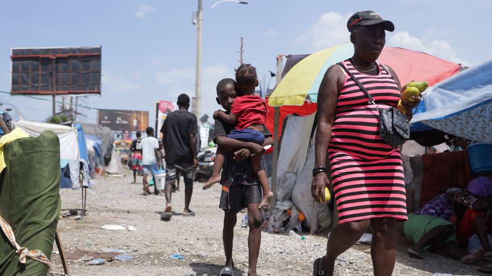 epa13005852 Families displaced by violence walk through makeshift housing area near Toussaint Louverture International Airport in Port-au-Prince, Haiti, 30 May 2026. The resumption of commercial flights between the Dominican Republic and Haiti, which took effect on Saturday, will mark an important step forward in relations between the two neighboring countries.  EPA/Patrice Noel