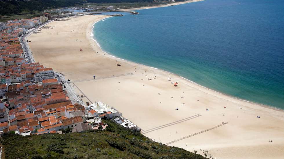 Sem sol e com poucos banhistas, a época balnear arrancou hoje com mais gente na marginal e nas esplanadas do que na praia da Nazaré, onde não falta espaço para cumprir distâncias de segurança, Nazaré, Leiria, 6 de junho de 2020. Com algumas nuvens a toldar o sol e a tornar a praia menos convidativa, era na marginal da Nazaré que manhã cedo se concentrava o movimento, com passeantes e atletas a cruzarem-se no passeio largo. PAULO CUNHA /LUSA
