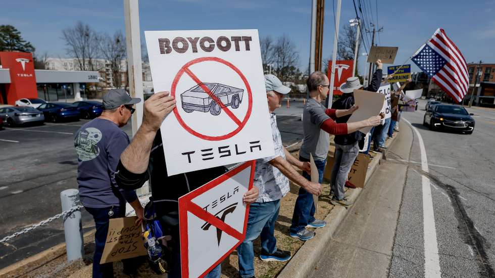 epa11949927 Demonstrators gather outside a Tesla dealership to protest businessman Elon Musk's current role in US President Donald Trump's administration in Decatur, Georgia, USA, 08 March 2025. Musk is leading the Department of Government Efficiency (DOGE) and has come under criticism for wide-scale government layoffs and downsizing.  EPA/ERIK S. LESSER