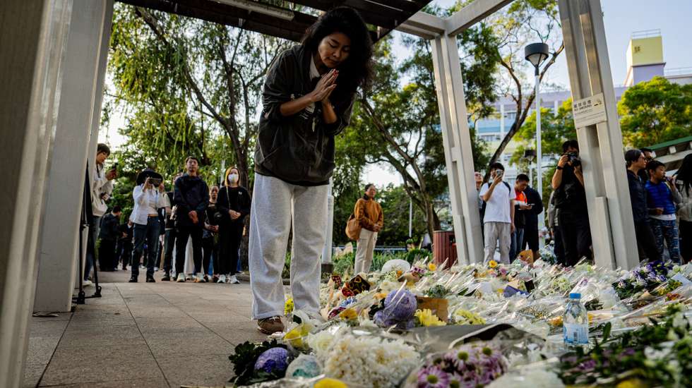epa12556656 A woman prays for victims of the fire at Wang Fuk Court residential estate in Tai Po district in Hong Kong, China, 29 November 2025. The city is mourning 128 people killed in the high-rise apartment fire, with about 200 others still unaccounted for.  EPA/LEUNG MAN HEI