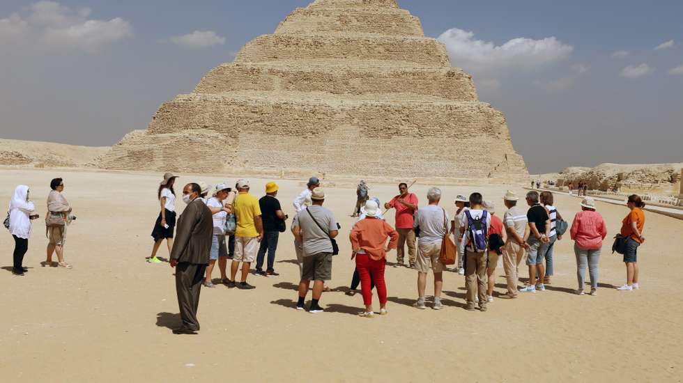epa09467606 A group of tourists gathers outside Tomb of King Djoser step pyramid, that was reopened for visitors after a restoration, in the Saqqara area, near Giza, Egypt, 14 September 2021. An information plate by the Ministry of Tourism &amp; Antiques at the entrance of the site describes the ancient Southern Tomb step pyramid, also known as the Saqqara pyramid, as being 'the oldest stone building of the ancient world' which was 'discovered by the English archaeologist Cecil Malaby Firth in 1928.' A series of corridors with even some false doors are described as the 'most important architectual and decorative elements' in the tomb that also features a 7.5 x 7.5m burial chamber at a depth of some 31 meters with a sarcophagus made of 16 blocks of pink granite and a height of about 3.6 meters.  EPA/KHALED ELFIQI  HANDOUT EDITORIAL USE ONLY/NO SALES
