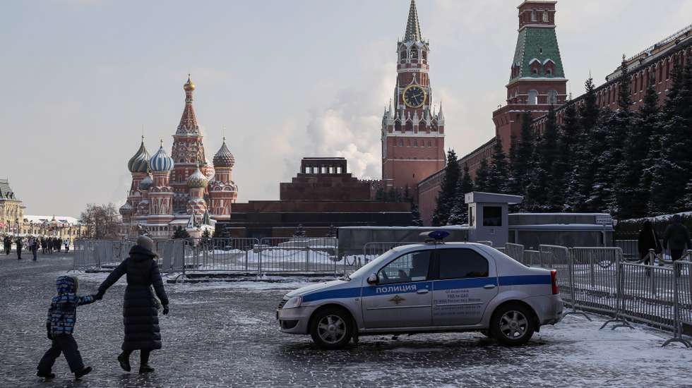epa10481580 A woman and a child walk past a police car parked on the Moscow Red Square in Moscow, Russia, 21 February 2023.  EPA/YURI KOCHETKOV