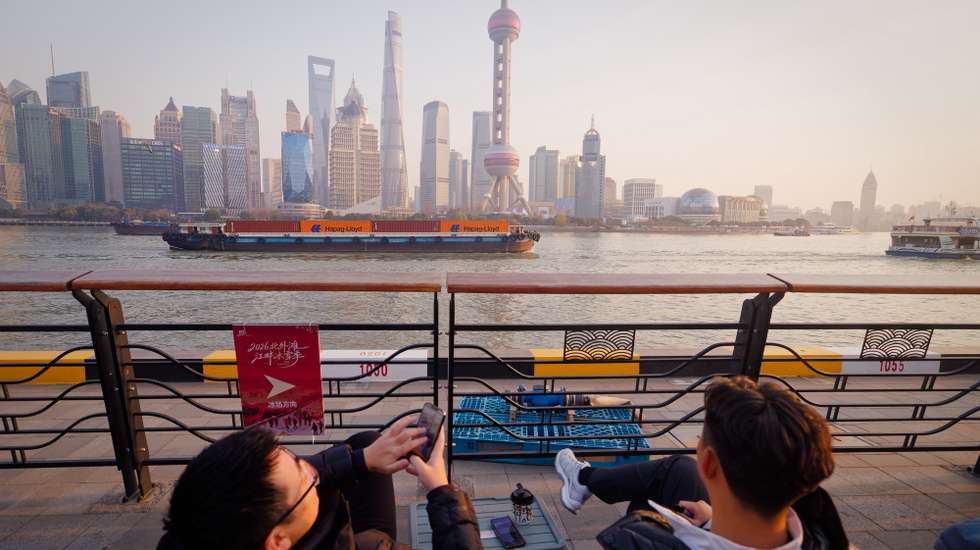 epaselect epa12647827 People in cafe watch cargo ships passing by on Huangpu River, in Shanghai, China, 13 January 2026 (issued 14 January 2026). According to the General Administration of Customs, China’s trade surplus reached a record $1 trillion in the first 11 months of the year, with exports rising 5.4 percent and imports falling 0.6 percent; the November surplus stood at $112 billion, the third largest on record.  EPA/ALEX PLAVEVSKI