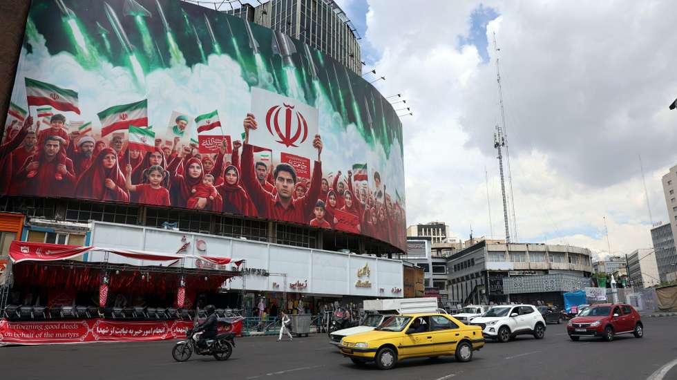 epa12871331 Iranians drive past a large political billboard displaying Iran's national flags at Valiasr Square in Tehran, Iran, 06 April 2026. The US president has given Iran a 48-hour deadline to reach a deal and reopen the Strait of Hormuz.  EPA/ABEDIN TAHERKENAREH