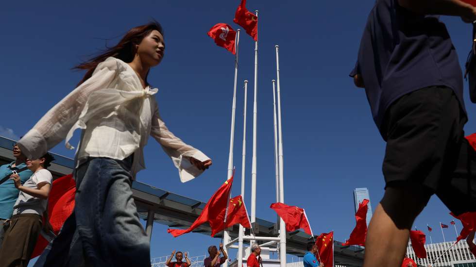 epa13274336 People walk pass Chinses and Hong Kong flags in Hong Kong, China, 01 October, 2026. The city celebrates China's National Day on 01 October 2026, marking the 77th founding anniversary of the People's Republic of China.  EPA/MAY JAMES