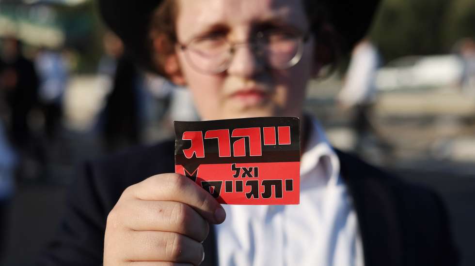epa11441736 A sign reading 'We will not enlist' as Ultra-Orthodox Jews are detained by police as they block highway 4 in Bnei Brak, near Tel Aviv, Israel, 27 June 2024. The protest was against the recruitment of Ultra-Orthodox Jews into the army following a ruling by the Israeli Supreme Court that ultra-Orthodox Jews must also be conscripted into military service.  EPA/ATEF SAFADI