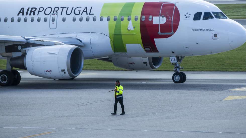 Um trabalhador de placa dá indicações a um piloto num avião da TAP, no Aeroporto Humberto Delgado, em Lisboa, 15 de abril de 2025.  JOSÉ SENA GOULÃO/LUSA