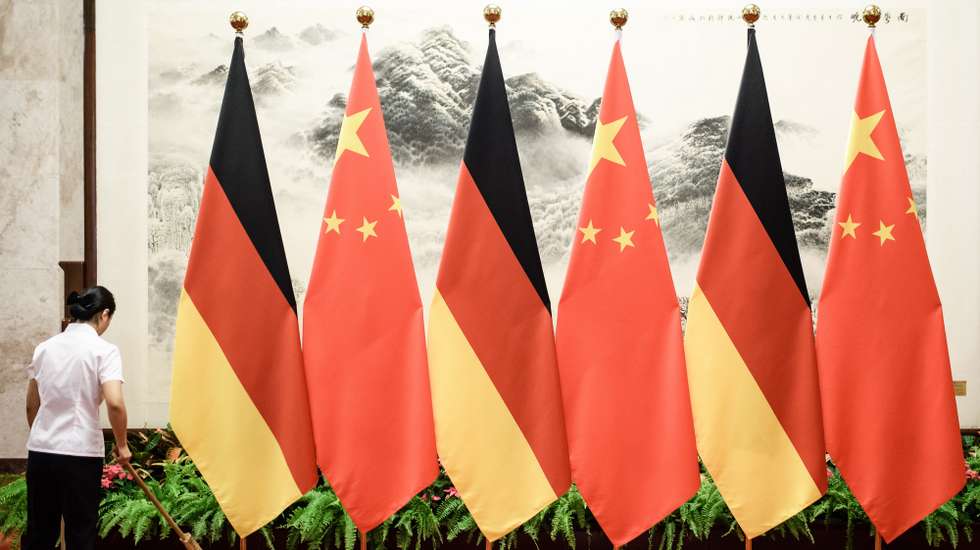 epa07821803 A cleaning aid sweeps with a broom next to a row of flagpoles displaying the German and Chinese flags prior to a welcome ceremony with military honors for German Chancellor Angela Merkel, held by Chinese Premier Li Keqiang (both not pictured) at the Great Hall of the People in Beijing, China, 06 September 2019. German Chancellor Angela Merkel in on a visit to China from 06 to 07 September 2019.  EPA/CLEMENS BILAN
