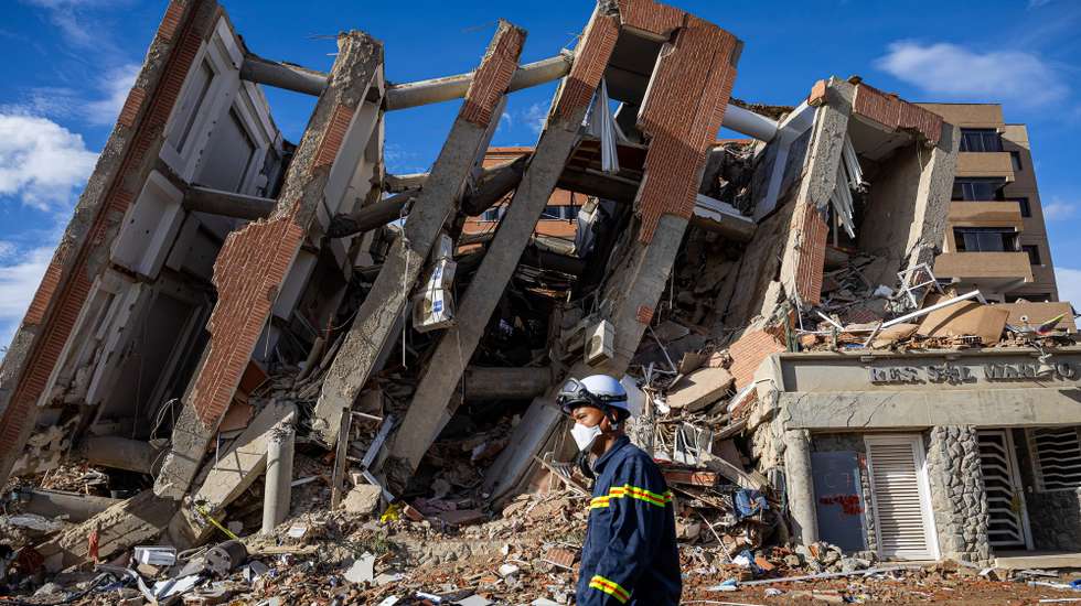 epa13076091 A Vietnamese rescuer walks past the rubble of destroyed buildings in the wake of two earthquakes measuring magnitudes 7.2 and 7.5 in Catia La Mar, La Guaira, Venezuela, 30 June 2026. The death toll from the earthquakes that struck northern Venezuela on 24 June 2026 has risen to 1,943, according to the President of the National Assembly, Jorge Rodriguez.  EPA/MIGUEL GUTIERREZ