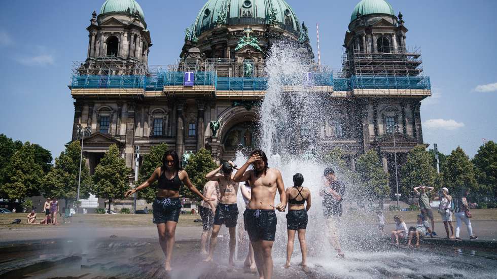 epa10022118 Tourists from the United States cool off in a fountain at Lustgarten park in Berlin, Germany, 19 June 2022. The German Weather Service (Deutscher Wetterdienst) warns of an early heatwave with highs of 38 degrees Celsius in Germany.  EPA/CLEMENS BILAN