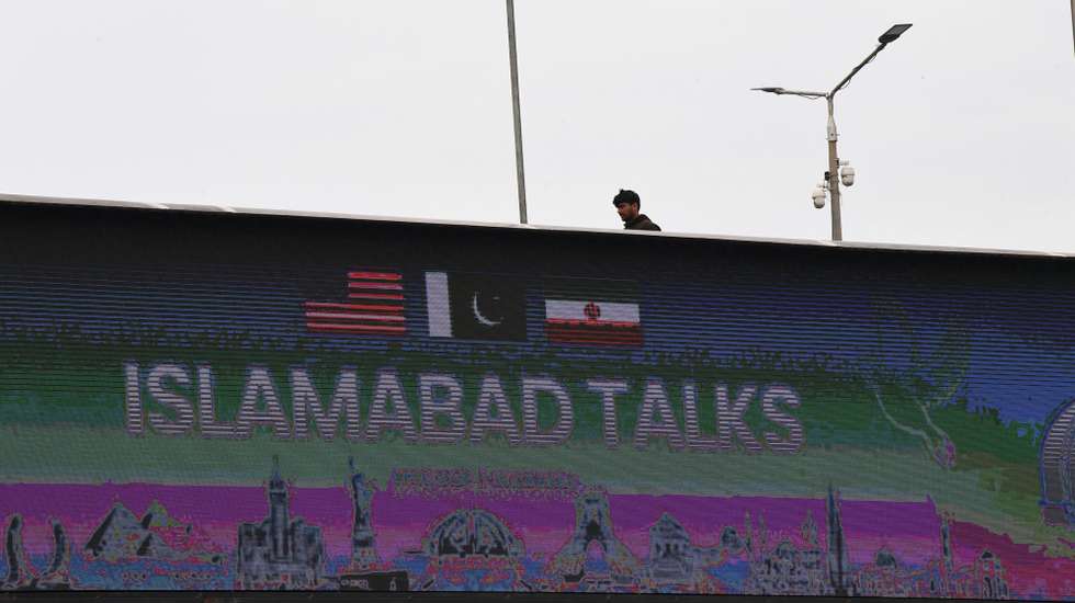 epa12882439 A man walks past a billboard near the media centre as delegations from the United States and Iran begin peace talks in Islamabad, Pakistan, 11 April 2026. An Iranian and US delegation arrived in Islamabad for planned peace talks amid a fragile two-week ceasefire following the conflict that began on 28 February 2026.  EPA/ZAYAN SHEIKH