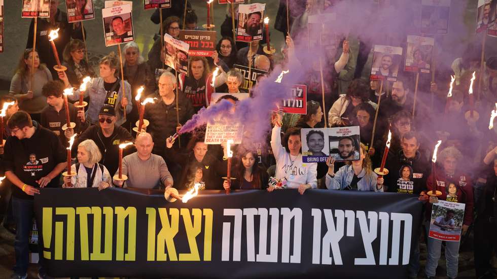 epa11826740 Family members of hostages held by Hamas in Gaza and their supporters light torches as they react to ceasefire reports during a protest calling for a ceasefire and for the release of the hostages, outside the Likud party headquarters in Tel Aviv, Israel, 15 January 2025. According to US and Hamas officials, Israel and Hamas agreed on a hostage deal and ceasefire. The banner reads 'get them out of Gaza and get out of Gaza.'  EPA/ABIR SULTAN