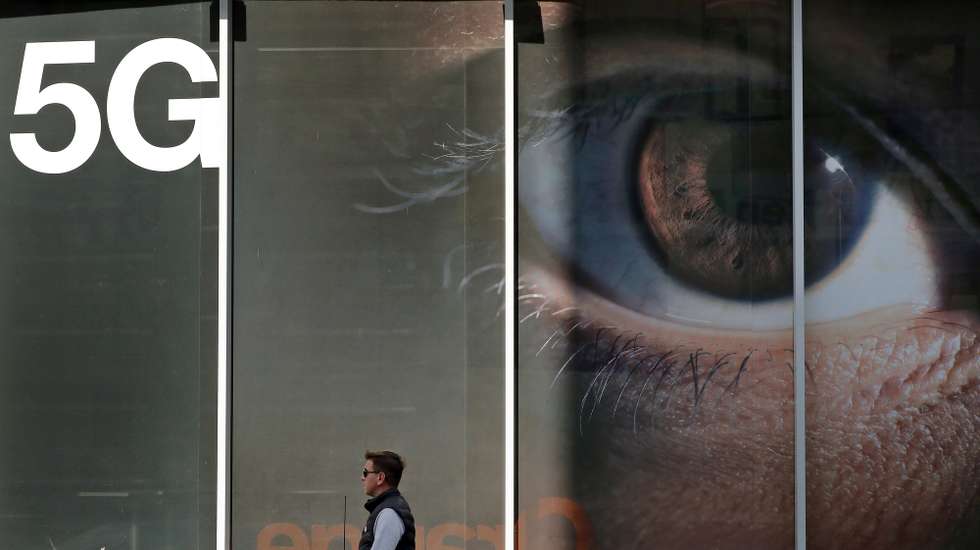 epa08757561 A Romanian man passes in front of a shop window of an Orange store that displays a huge 5G advertise banner, in Bucharest, Romania, 19 October 2020. Romania was among the first countries in the EU where local mobile communications operators launched commercial 5G services, through upgrades of 4G networks, using the radio spectrum they currently have in 2019, as The National Authority for Management and Regulation in Communications (ANCOM) failed to properly organize an auction for the rest of the frequency bands necessary for mobile operators to implement the 5G standard at the announced optimal parameters. The communication business sector is waiting for a new auction to be organized until the end of 2020. Mobile internet traffic is doubling in Romania every year.  EPA/ROBERT GHEMENT