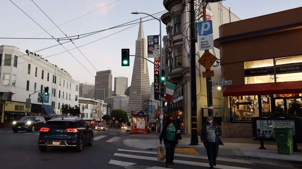 epa08853920 Pedestrians walk across a street in North Beach, as the Transamerica Pyramid building looms in the background, in San Francisco, California, USA, 30 November 2020. San Francisco is preparing for the most restrictive COVID-19 reopening tier (Purple), joining other Bay Area counties in a California curfew prohibiting non-essential business and personal gatherings from 10pm to 5am to help stop the spread the coronavirus, as the state is seeing the high rates of positive cases and hospitalizations.  EPA/JOHN G. MABANGLO