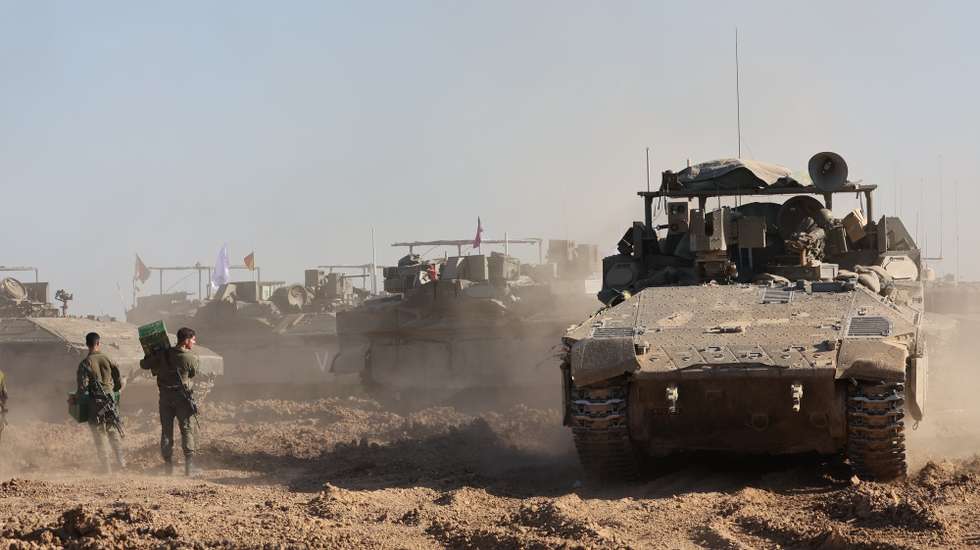 epa11211360 Israeli soldiers walk next to their military vehicles near the border fence with the Gaza Strip, as seen from the Israeli side in southern Israel, 10 March 2024. More than 31,000 Palestinians and over 1,300 Israelis have been killed, according to the Palestinian Health Ministry and the Israel Defense Forces (IDF), since Hamas militants launched an attack against Israel from the Gaza Strip on 07 October 2023, and the Israeli operations in Gaza and the West Bank which followed it.  EPA/ABIR SULTAN