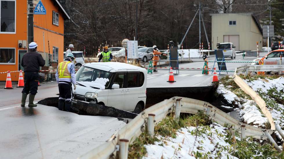 epaselect epa12579757 Workers gather at a collapsed road in Tohoku, Aomori prefecture, northeastern Japan, 09 December 2025. A powerful quake with a magnitude of 7.5 hit northeastern Japan late 08 December 2025, triggering tsunami warnings in coastal areas of northeast Japan and Hokkaido. More than 30 people had been injured in the late-night earthquake.  EPA/JIJI PRESS JAPAN OUT EDITORIAL USE ONLY/