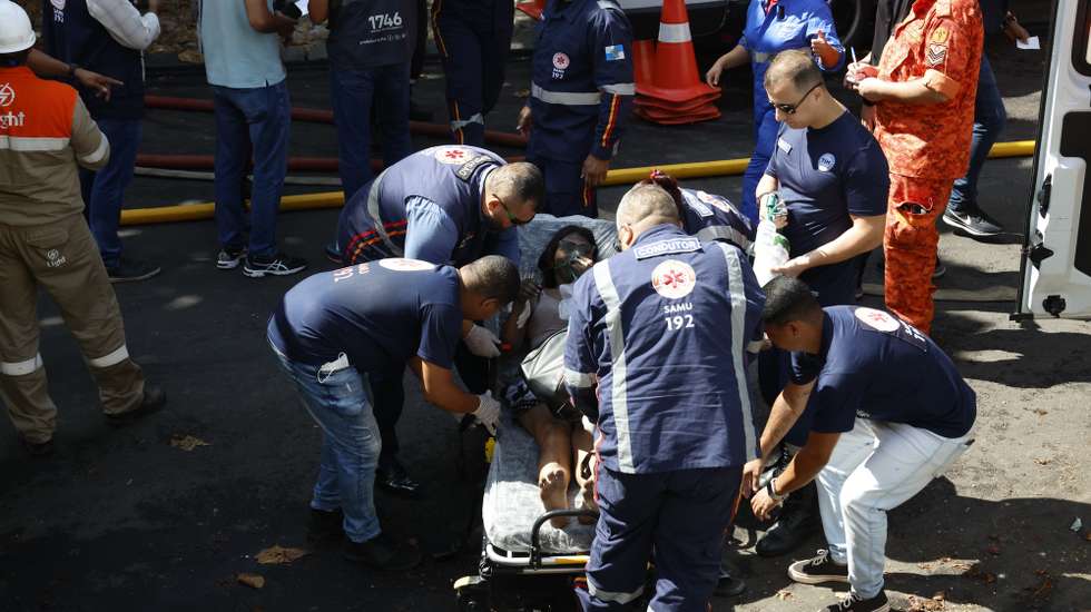epa11890902 A person is treated by medical staff after a fire in a textile factory in Rio de Janeiro, Brazil, 12 February 2025. The fire broke out in the textile factory specializing in carnival costumes.  EPA/Antonio Lacerda