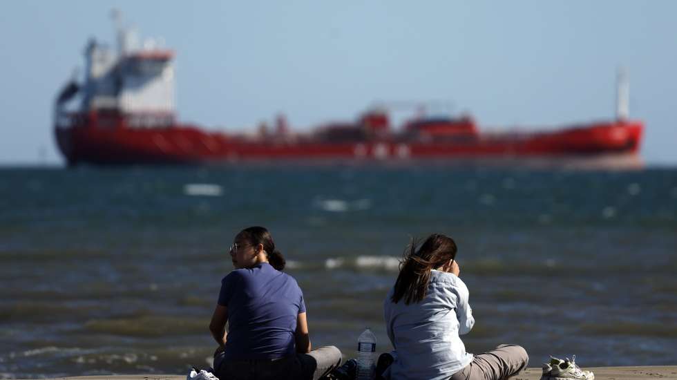 epa12947920 Women sit on a beach in front of an oil tanker near the port in Fos-sur-Mer, Southern France, 11 May 2026. Due to the conflict in the Middle East, the international oil benchmark Brent Crude surged past 103 US dollars per barrel. The hike follows a surge in global oil prices and supply disruptions in the Strait of Hormuz linked to the ongoing conflict involving Iran, Israel, and the United States.  EPA/GUILLAUME HORCAJUELO