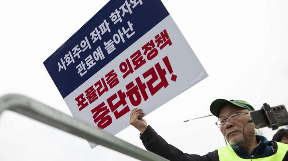 epa11186116 A Doctor of Gyonggi-do medical association holds a sign reading 'Stop Populism medical policy', during a protest against the government's medical policy, near the presidential office in Seoul, South Korea, 28 February 2024. South Korean hospitals earlier in February turned away patients and delayed surgeries, amid spiking tensions between doctors and the government over the latter's plan to increase the number of medical students. More than half of the country's 13,000 trainee doctors submitted their resignations on 20 February in protest of the plan, citing pay and overworking conditions.  EPA/JEON HEON-KYUN
