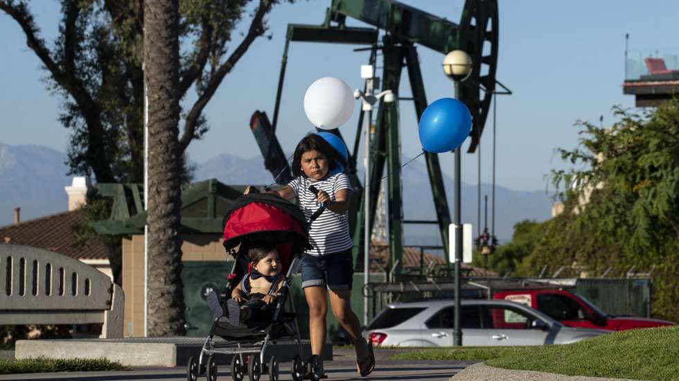 epa07874195 Kids play in the Hilltop Park next to a pumpjack in Signal Hill, Los Angeles, California, 14 August 2019.  (issued 27 September 2019) With nearly 6,000 active oil and gas wells in the county, according to a Natural Resources Defense Council, Los Angeles remains the largest urban oil field in the US. Of the 18 million people leaving in greater Los Angeles, 600,000 live less than 400 meters from an active well.  The story of the city is deeply intertwined with the oil industry. Old documents show Venice Beach covered with rigs and people walking the streets wearing gasmasks because the air pollution was so intense. This situation led to California being able to edict its own gas emission standards, stricter than those in the rest of the country, to counter the disastrous impact of the combined effects of oil production and traffic. This status was recently revoked by President Trump, a decision that is currently being challenged by the state of California.  EPA/ETIENNE LAURENT