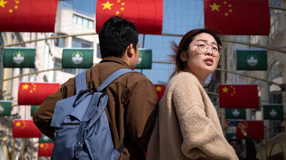 epa11785051 People walk past Chinese flags during the visit of the Chinese President to celebrate the 25th anniversary of the establishment of the Macau Special Administrative Region (MSAR) in Macau, China, 19 December 2024.  EPA/GONCALO LOBO PINHEIRO