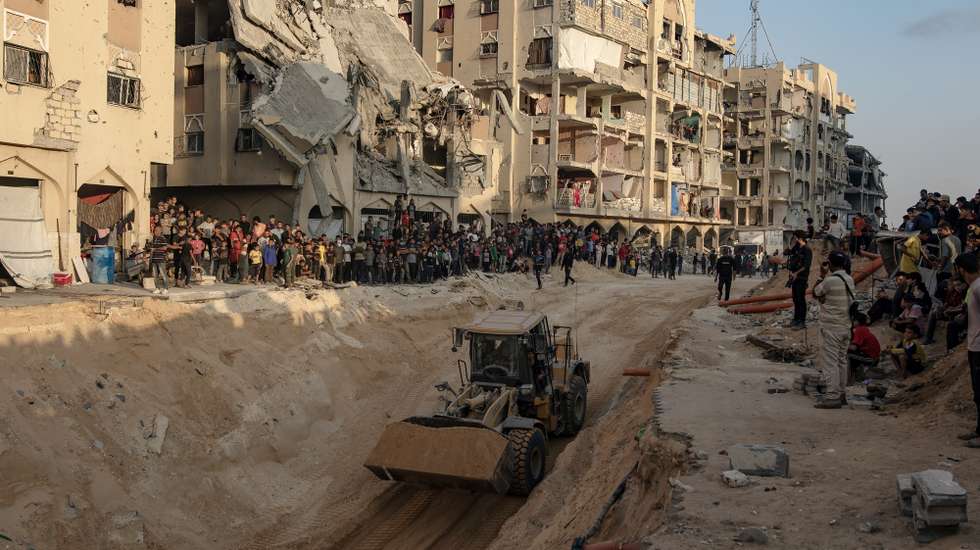 epaselect epa12460750 Locals gather to watch as an excavator works at the site where members of the Al-Qassam Brigades, the military wing of the Hamas movement, are searching for the bodies of Israeli hostages in an area in Hamad City, Khan Younis, in the southern Gaza Strip, 17 October 2025.  EPA/HAITHAM IMAD