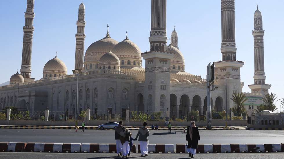epa12621077 People walk past the Al-Shaab Mosque in Sana'a, Yemen, 01 January 2026. The Al-Shaab Mosque was constructed 17 years ago on an area of 27,300 square meters and accommodates 44,000 worshippers. It is the largest mosque in Yemen, featuring 23 domes of different sizes and six distinctive mud-brick minarets.  EPA/YAHYA ARHAB