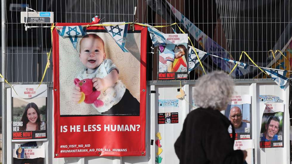 epa11087295 People walk past a picture of Israeli toddler Kfir Bibas who is held hostage by Hamas in Gaza as people attend to celebrate baby's birthday, outside the Kirya military base in Tel Aviv, Israel, 18 January 2024. Attendees were also calling for the immediate release of all hostages. The Bibas family, mother Shiri Bibas, her husband Yarden Bibas along with their children Kfir who turned one and four-year-old boy Ariel, were kidnapped by Hams from their home in Kibbutz Nir Oz during the attack on 07 October 2023. According to the Israeli army, 133 Israelis are still held hostage by Hamas in Gaza.  EPA/ABIR SULTAN