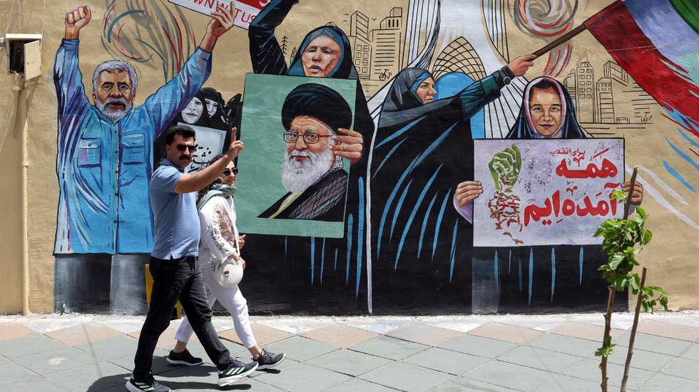 epaselect epa12940973 An Iranian couple walks next to a anti-US and Israel mural in a street in Tehran, Iran, 08 May 2026. Iran and US exchanged fire in the Strait of Hormuz amid a ceasefire.  EPA/ABEDIN TAHERKENAREH