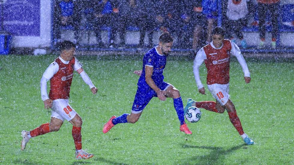 O jogador do Rebordosa, Miguel Silva (C), disputa a bola com os jogadores do Sporting de Braga, André Castro (E) e Vitor Carvalho, durante o jogo da 3.ª eliminatória da Taça de Portugal de futebol, no Complexo Desportivo de Azevido em Rebordosa, Paredes, 19 de outubro 2023. ESTELA SILVA/LUSA