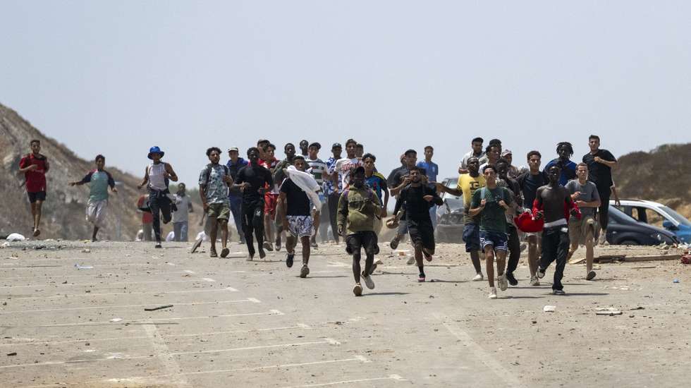 epa13144366 Young men attempt to storm the Bab Sebta border crossing near Fnideq, Morocco, 31 July 2026. The disturbances erupted as thousands gathered near the border, and some people attempted to cross into Ceuta and clashed with Moroccan security forces.  EPA/JALAL MORCHIDI