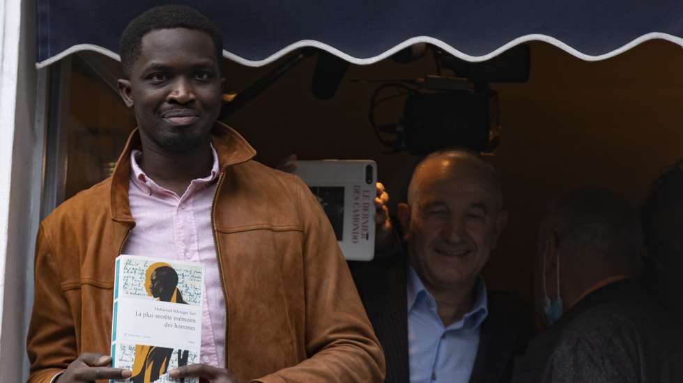 epa09561531 Senegalese-French writer Mohamed Mbougar Sarr (L) poses at the window of the Drouant restaurant after winning the Goncourt Literary Prize 2021 for his book 'La Plus Secrete Memoire des Hommes (The Most Secret Memory of Man)', in Paris, France, 03 November 2021. The Prix Goncourt is given annually to an author by the French literary organization 'Societe litteraire des Goncourt'.  EPA/IAN LANGSDON
