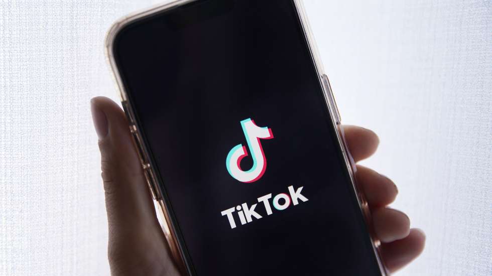 epa10635388 In this photo illustration a person holds up a cell phone with the TikTok logo displayed in Los Angeles, California, USA, 17 May 2023. Govenor Greg Gianforte of Montana signed a measure that bans the TikTok app in the state.  EPA/CAROLINE BREHMAN