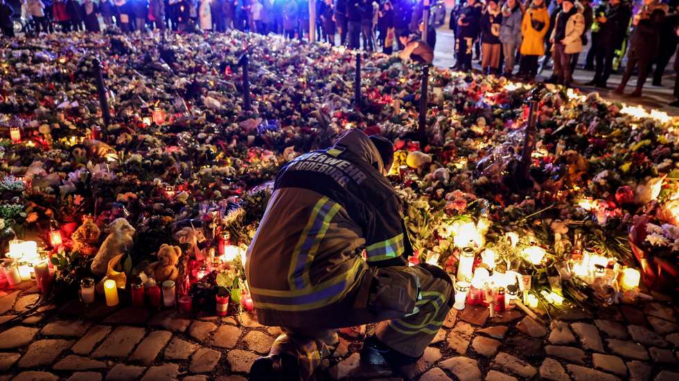 epaselect epa11791323 A firefighter in front of candles and flowers at the mourning site in front of St. John's Church following a vehicle-ramming attack on the Christmas market in Magdeburg, Germany, 23 December 2024. According to Saxony-Anhalt State Premier Haseloff, five people were confirmed dead and at least 235 were injured after a car was driven into a crowd at Magdeburg's Christmas market on 20 December. The suspect, a Saudi national, was taken into custody.  EPA/FILIP SINGER