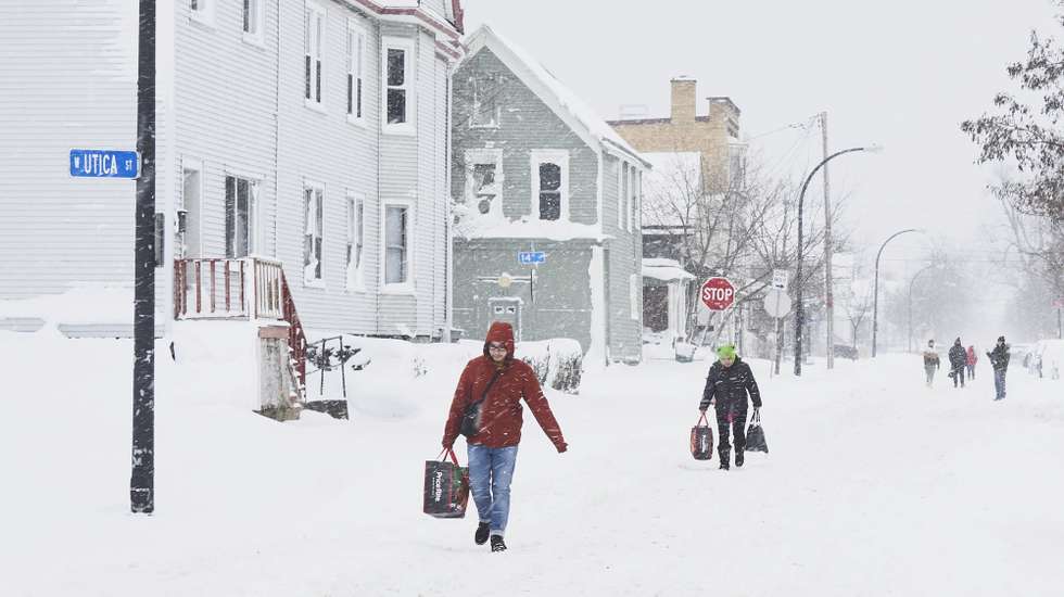 epa10378754 People carry groceries along a snow covered  Massachusetts Avenue in West Buffalo as the effects of a massive winter storm which has affected large portions of the United States, continues in Buffalo, New York, USA, 26 December 2022. Much of the United States is currently experiencing some sort of winter weather as result of the large storm which was generated by a bomb cyclone, the meteorological phenomenon when the atmospheric pressure quickly drops in a strong storm  EPA/JOSH THERMIDOR
