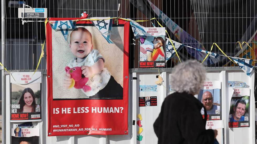 epa11087295 People walk past a picture of Israeli toddler Kfir Bibas who is held hostage by Hamas in Gaza as people attend to celebrate baby's birthday, outside the Kirya military base in Tel Aviv, Israel, 18 January 2024. Attendees were also calling for the immediate release of all hostages. The Bibas family, mother Shiri Bibas, her husband Yarden Bibas along with their children Kfir who turned one and four-year-old boy Ariel, were kidnapped by Hams from their home in Kibbutz Nir Oz during the attack on 07 October 2023. According to the Israeli army, 133 Israelis are still held hostage by Hamas in Gaza.  EPA/ABIR SULTAN