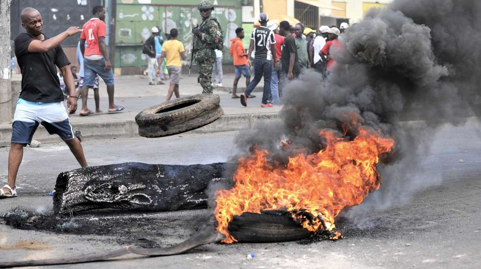 epa11760099 Smoke rises from burning tires and barricades as military personnel and demonstrators stand nearby during a post-election protest in a street of Maputo, Mozambique, 06 December 2024. In recent weeks, supporters of former presidential candidate Venancio Mondlane, who is currently in exile, have taken to the streets of the Mozambican capital to challenge the results of the disputed general election held in October 2024.  EPA/LUISA NHANTUMBO