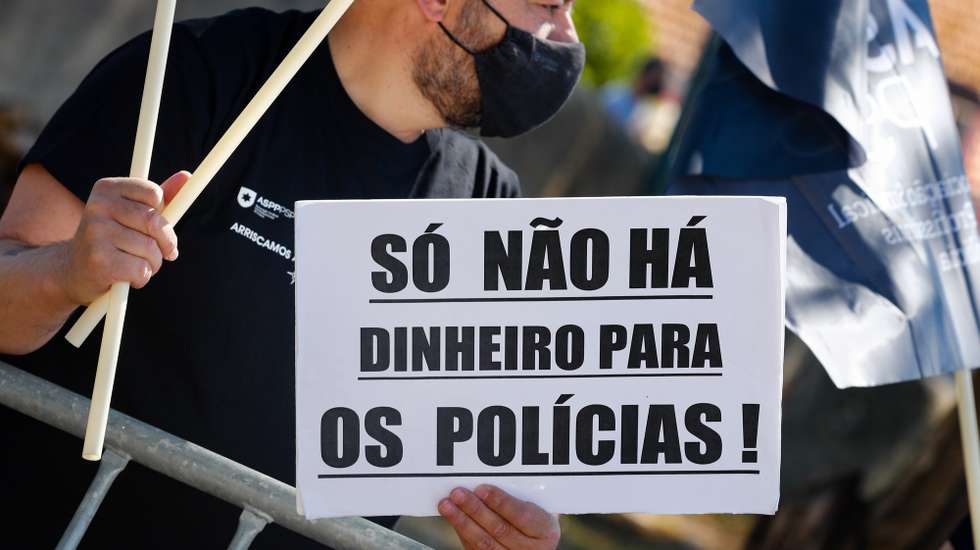 Um participante exibe um cartaz onde se lê "Só Não Há Dinheiro Para Os Polícias!" durante a jornada de protesto dos elementos da PSP e da GNR com o objetivo de "sensibilizar todos os cidadãos para a problemática da não atribuição do suplemento de risco aos polícias da PSP e militares da GNR", junto ao Palácio da Ajuda, local onde decorre a reunião do Conselho de Ministros, em Lisboa, 15 de julho de 2021. Convocado pelos sindicatos da Polícia de Segurança Pública (PSP) e associações da Guarda Nacional Republicana (GNR) - Associação Nacional de Guardas; Associação Nacional de Sargentos da Guarda Associação Sócio Profissional Independente dos Profissionais da GNR; Associação Sindical Autónoma de Polícias; Organização Sindical dos Polícias; Sindicato Independente de Agentes de Polícia; Sindicato Independente Livre Polícia; Sindicato Nacional da Polícia; Sindicato Nacional Carreira de Chefes PSP; Sindicato Nacional Oficiais de Polícia; Sindicato Profissionais de Polícia; Sindicato de Polícia pela Ordem e Liberdade; Sindicato Vertical da Carreira de Polícia. ANTÓNIO COTRIM/LUSA