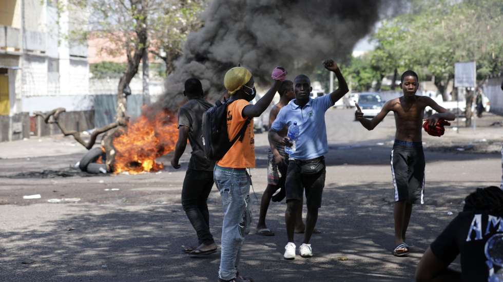 epa10942945 Demonstrators shout slogans as a pile of tires burns in the background during clashes between the protesters and policemen at protest in repudiation of the results of the sixth municipal elections in Maputo, Mozambique, 27 October 2023. The National Elections Commission (CNE) of Mozambique declared the triumph of the ruling party, Frelimo, in 64 out of the country's 65 municipalities on 26 October.  EPA/LUISA NHANTUMBO