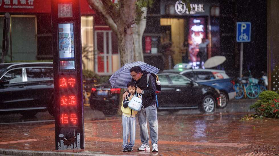 epaselect epa11695505 People shelter under an umbrella as they wait at a traffic light during heavy rain due to Typhoon Kong-rey in Shanghai, China, 01 November 2024. After sweeping through Taiwan on 31 October, Typhoon Kong-rey is approaching China's east coast, with Shanghai bracing for heavy rainfall and strong winds. Some high-speed train services were suspended starting from 31 October and citizens were alerted by authorities to stock up on drinking water and food.  EPA/ALEX PLAVEVSKI