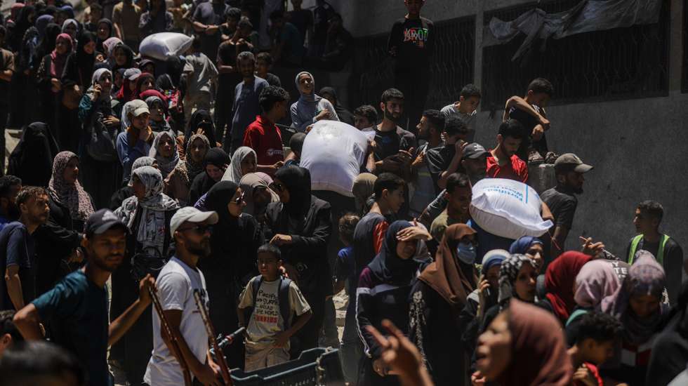 epa12198721 Displaced Palestinians wait to receive aid through the WFP after it successfully arrived at the organization’s warehouses in Gaza City, 26 June 2025. According to the UN half a million people, or one in five people in the Strip are facing starvation while the entire population of the Gaza Strip continues to face a critical risk of famine following 19 months of conflict, mass displacement and severe restrictions on humanitarian aid.  EPA/MOHAMMED SABER
