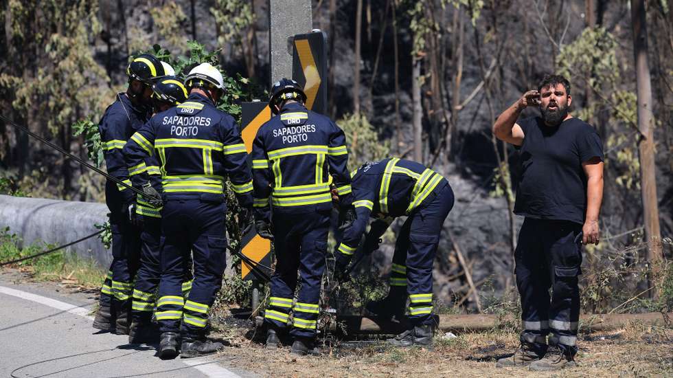 epa12273254 Firefighters remove communications cables that were preventing cars from getting through durig a forest fire in Arouca, Portugal, 30 July 2025.The fire that has been raging in Arouca, in the district of Aveiro, has three active fronts and has already reached the parish of Santa Eulalia, the local authority said.  EPA/ESTELA SILVA