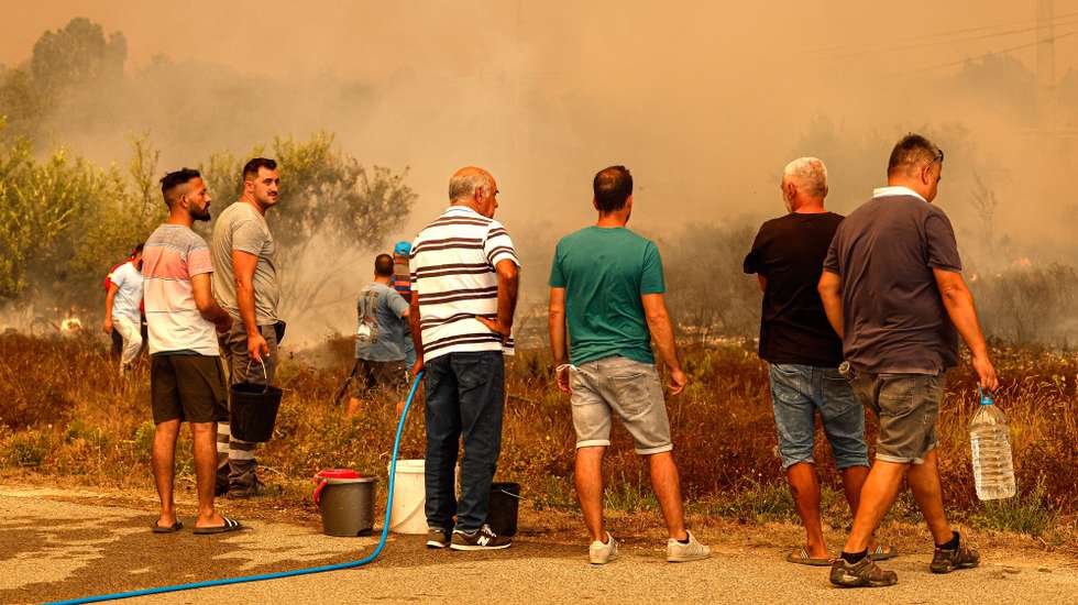 epa10789278 People watch the fire in the municipality of Odemira, 07 August 2023.  The fire, which broke out in the Baiona area, in the parish of SÃ£o TeotÃ³nio, 05 August, has already forced the evacuation of four locations in the municipality of Odemira (Vale dos Alhos, Vale de Ãgua, ChoÃ§a dos Vales and Relva Grande) and a rural tourism unit.  EPA/LUIS FORRA